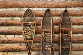 Snow shoes hanging on a log cabin