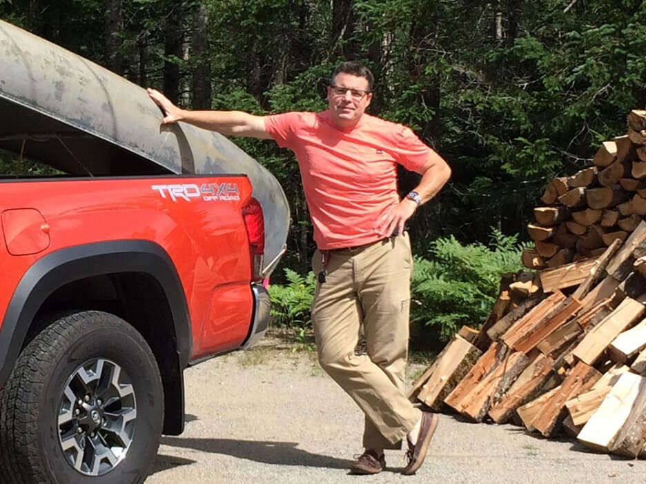 Jason Barden standing next to red pickup truck with canoe on back