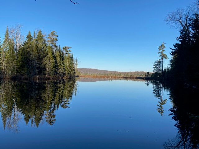 island and mountain reflection on still lake