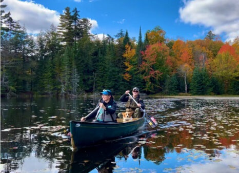 Two people in a canoe paddling at Twin Ponds Preserve in the Adirondacks